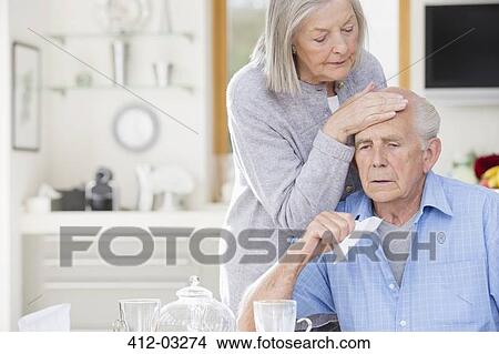 Older woman feeling sick husband's forehead View Large Photo Image Picture - Older woman feeling sick husband's forehead. Fotosearch