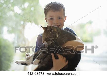 Smiling boy holding cat indoors View Large Photo Image Stock Photo - Smiling boy holding cat indoors. Fotosearch