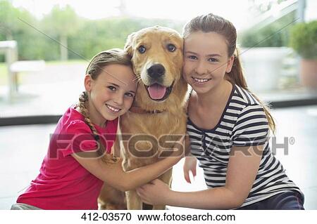 Smiling girls hugging dog indoors View Large Photo Image Stock Image - Smiling girls hugging dog indoors. Fotosearch