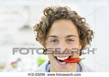 Smiling man holding chili pepper in mouth View Large Photo Image Stock Photography - Smiling man holding chili pepper in mouth. Fotosearch