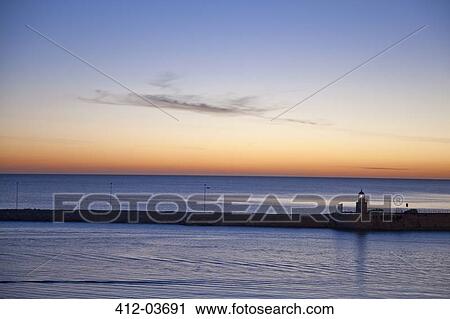 Stock Image - Sunrise sky over still ocean. Fotosearch