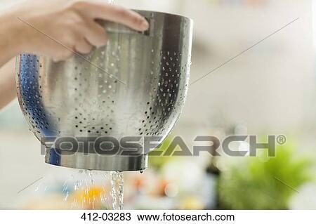 Woman straining food in kitchen View Large Photo Image Stock Image - Woman straining food in kitchen. Fotosearch