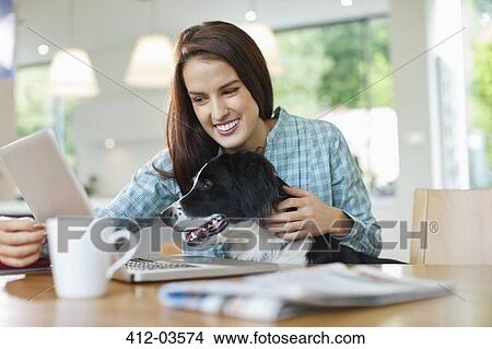 Woman with dog on lap using laptop View Large Photo Image Picture - Woman with dog on lap using laptop. Fotosearch