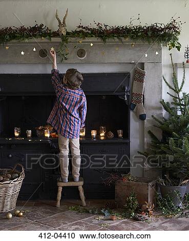 Boy decorating Christmas fireplace View Large Photo Image Stock Image - Boy decorating Christmas fireplace. Fotosearch