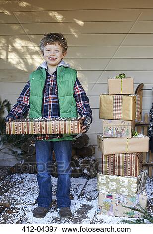 Stock Photo - Boy holding Christmas gifts on snowy porch. Fotosearch