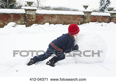 Boy making snowman outdoors View Large Photo Image Stock Image - Boy making snowman outdoors. Fotosearch