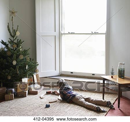 Boy playing with train by Christmas tree View Large Photo Image Stock Photography - Boy playing with train by Christmas tree. Fotosearch