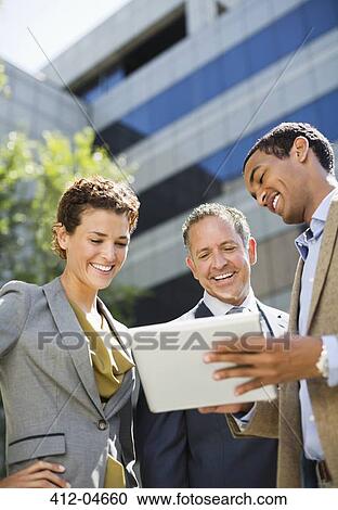 Stock Image - Business people using tablet computer outdoors. Fotosearch
