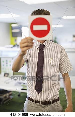 Businessman holding warning sign in office View Large Photo Image Stock Photography - Businessman holding warning sign in office. Fotosearch