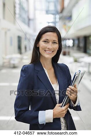 Businesswoman carrying folders in office View Large Photo Image Stock Photo - Businesswoman carrying folders in office. Fotosearch