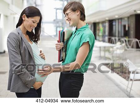 Businesswoman holding pregnant colleague's bell View Large Photo Image Picture - Businesswoman holding pregnant colleague's bell. Fotosearch