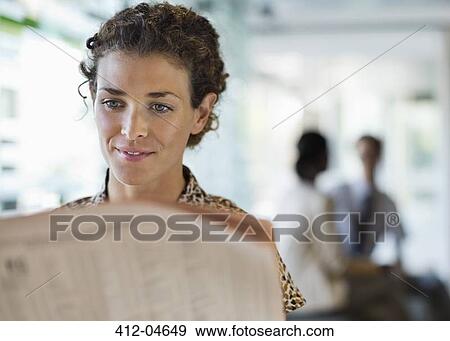 Stock Photo - Businesswoman reading newspaper at desk. Fotosearch
