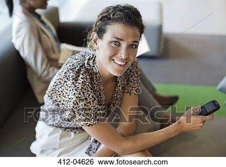 Stock Photograph - Businesswoman sitting on sofa in office. Fotosearch