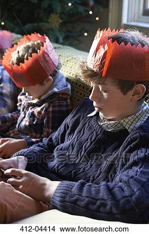 Picture - Children in paper crowns relaxing on sofa. Fotosearch