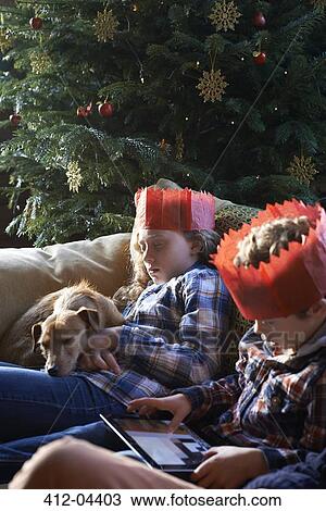 Stock Image - Children in paper crowns relaxing on sofa. Fotosearch