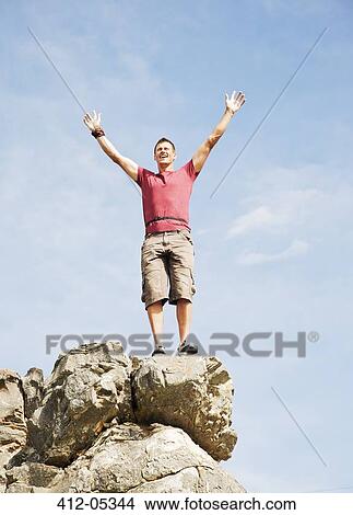 Picture - Climber cheering on rocky hilltop. Fotosearch