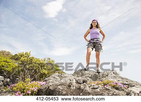 Stock Image - Climber standing on rocky hilltop. Fotosearch