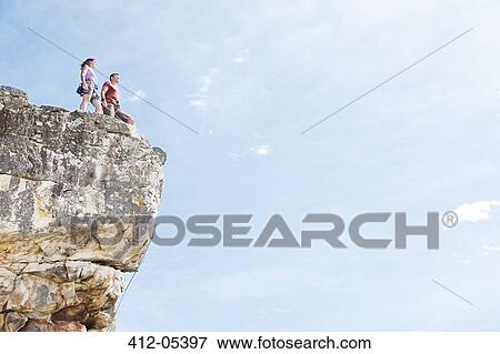 Stock Photo - Climbers standing on rocky hilltop. Fotosearch