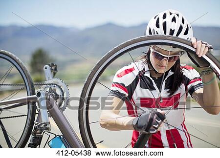Cyclist adjusting tire on rural road View Large Photo Image Stock Photo - Cyclist adjusting tire on rural road. Fotosearch