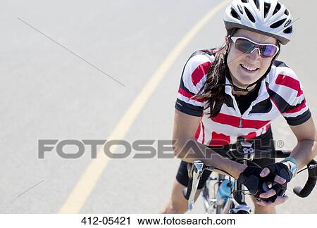 Stock Image - Cyclist smiling on rural road. Fotosearch
