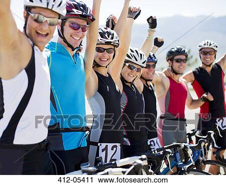 Stock Image - Cyclists cheering together outdoors. Fotosearch