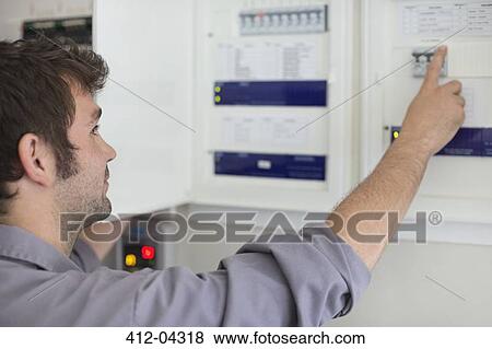 Stock Photo - Electrician examining control panel. Fotosearch