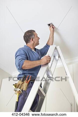 Electrician working on ceiling lights View Large Photo Image Stock Photograph - Electrician working on ceiling lights. Fotosearch