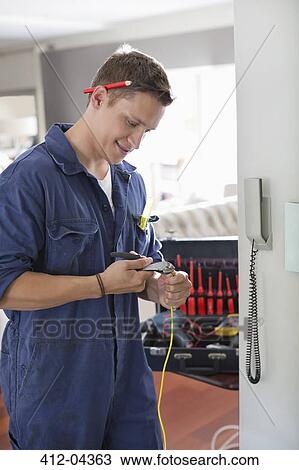 Electrician working on telephone in home View Large Photo Image Stock Image - Electrician working on telephone in home. Fotosearch