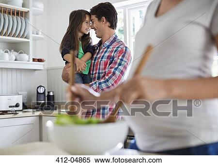 Stock Photography - Father and daughter touching noses in kitchen. Fotosearch