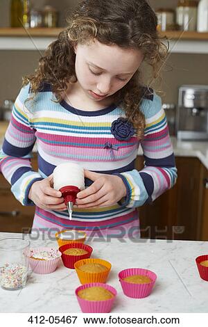 Girl decorating cupcakes in kitchen View Large Photo Image Stock Photo - Girl decorating cupcakes in kitchen. Fotosearch