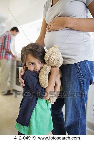 Stock Photo - Girl hiding behind pregnant mother. Fotosearch
