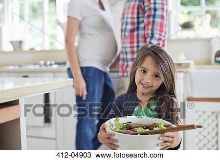 Girl holding bowl of salad in kitchen View Large Photo Image Stock Image - Girl holding bowl of salad in kitchen. Fotosearch
