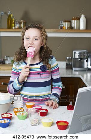 Stock Image - Girl licking spatula and baking. Fotosearch