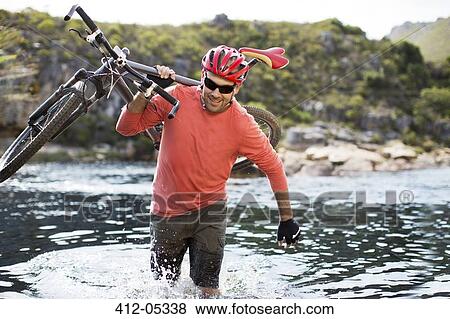 Man carrying mountain bike in river View Large Photo Image Stock Photo - Man carrying mountain bike in river. Fotosearch