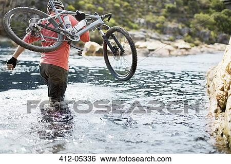Man carrying mountain bike in river View Large Photo Image Stock Photograph - Man carrying mountain bike in river. Fotosearch