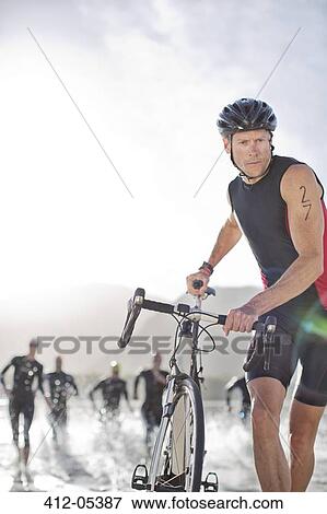Stock Photo - Man pushing bicycle on beach. Fotosearch