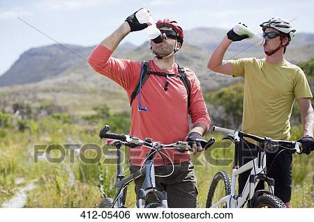 Stock Photograph - mountain bikers driving water in rural landscape. Fotosearch