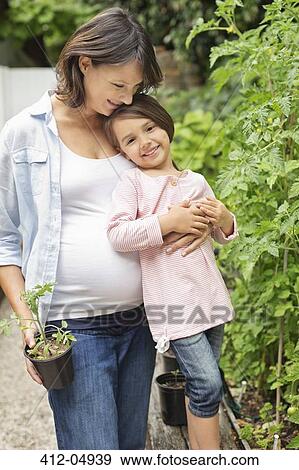 Pregnant mother and daughter gardening together View Large Photo Image Stock Photo - Pregnant mother and daughter gardening together. Fotosearch