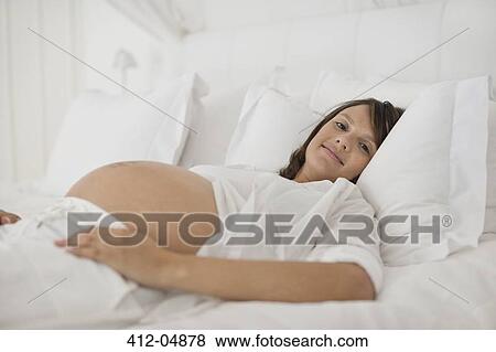 Pregnant woman laying on bed View Large Photo Image Stock Photo - Pregnant woman laying on bed. Fotosearch