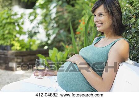 Stock Image - Pregnant woman relaxing outdoors. Fotosearch