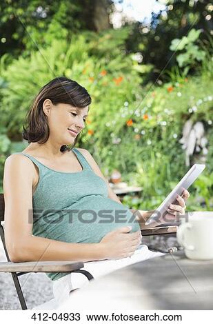 Pregnant woman using tablet computer outdoors View Large Photo Image Stock Image - Pregnant woman using tablet computer outdoors. Fotosearch