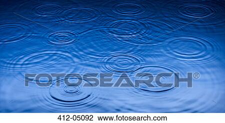 Stock Image - Ripples of raindrops in puddle. Fotosearch