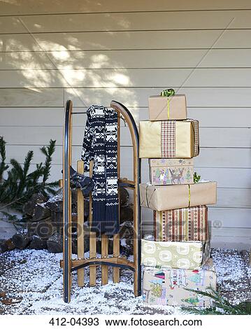 Stock Image - Scarf, wooden sled and Christmas gifts on snowy porch. Fotosearch