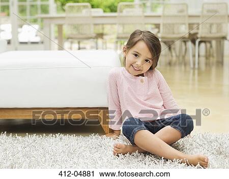 Stock Image - Smiling girl sitting on rug. Fotosearch