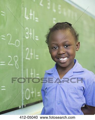 Stock Image - Student smiling at chalkboard. Fotosearch
