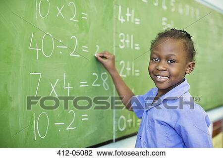 Stock Image - Student writing on blackboard in class. Fotosearch