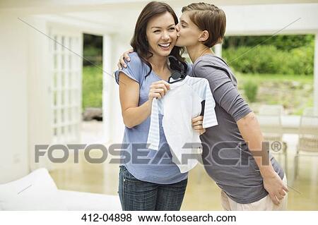Stock Photo - Woman giving pregnant friend baby clothes. Fotosearch