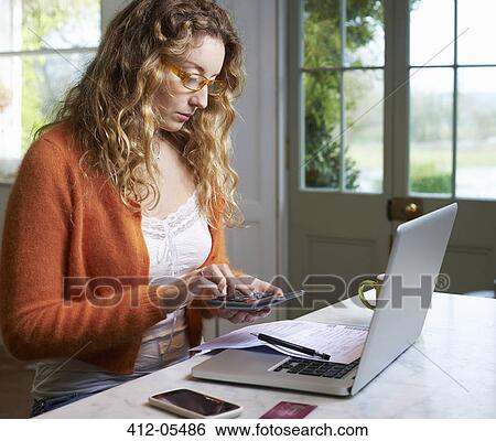 Stock Photograph - Woman paying bills on laptop. Fotosearch