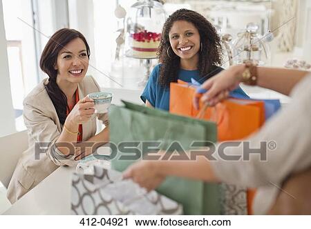 Stock Image - Woman showing friends shopping bags. Fotosearch