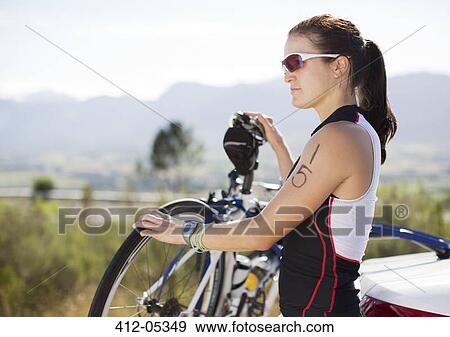 Woman standing with bicycle outdoors View Large Photo Image Stock Photo - Woman standing with bicycle outdoors. Fotosearch